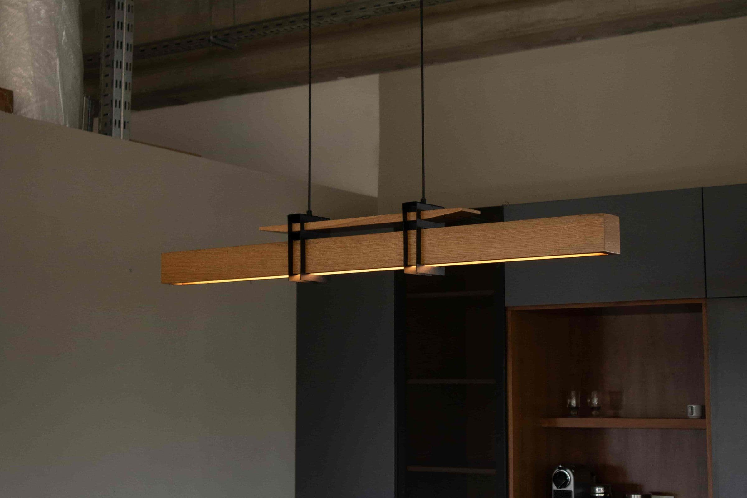 Lámpara colgante de madera Kanna sobre una mesa de comedor, con luz cálida debajo de la barra
